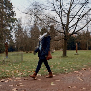 Eine Frau geht im Park. Ihr Gesicht ist unkenntlich gemacht. Sie erzählt, dass ihr Ehemann sie betrogen hat.
