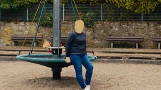 Lina sitzt auf dem Spielplatz. Ihr Gesicht ist unkenntlich gemacht.