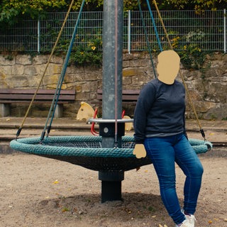 Lina sitzt auf dem Spielplatz. Ihr Gesicht ist unkenntlich gemacht.