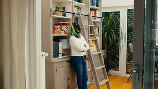 Eine Frau ist am Bücherregal angelehnt. Die Lehrerin ist anonymisiert und erzählt von ihrem Burnout.