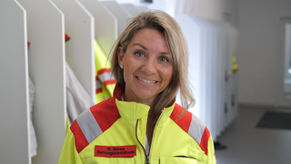 Ramona ist Quereinsteigerin im Rettungsdienst. Sie trägt ihre Einsatzbekleidung und lacht in die Kamera.