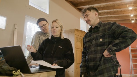 Das Paar Isabel und Aaron haben gemeinsam mit ihrem langjährigen Freund Chris einen Campingplatz in Isny übernommen. Während der Renovierungsarbeiten sind die drei zusammen vor einem Laptop zu sehen, an dem Isabel etwas erklärt.