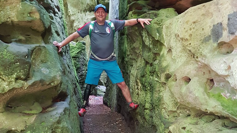 Fritz klettert auf einen Felsen mit seiner Beinprothese.  