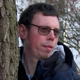 Junger Mann, der an einem Baum steht