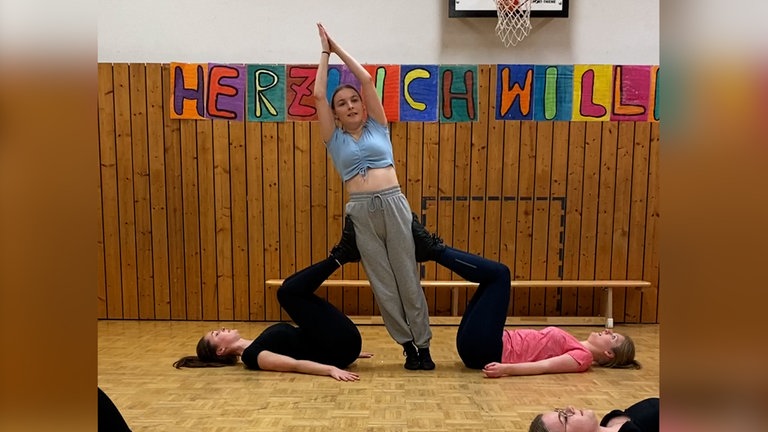 Drei Frauen machen Akrobatik in einer Turnhalle.