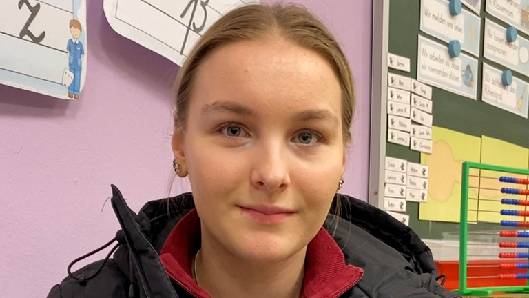 Junge Frau schaut in Kamera.