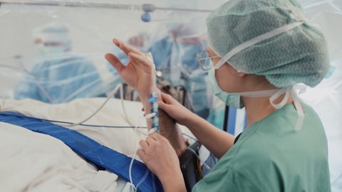 Bild aus dem Operationssaal. Eine Ärztin führt Bewegungen mit Thorstens Hand aus. 