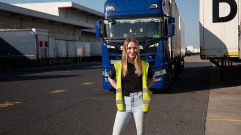 Junge Frau vor ihrem blauen Lastwagen