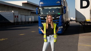 Junge Frau vor ihrem blauen Lastwagen