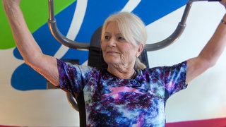 Seniorin Bärbel geht mit ihren 84 Jahren drei Mal pro Woche ins Gym. Sie trainiert an der Lastzugmaschine in einem Frauen-Fitnessstudio.