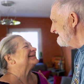 Michael und Ulrike sind ein weißes Paar mit grauen Haaren. Sie lachen sich gegenseitig an.
