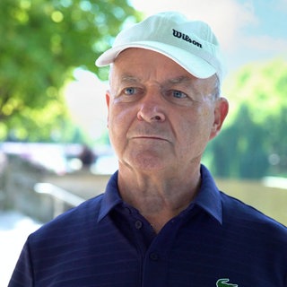 Mann mit Basecap steht vor der Kamera.