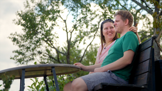 Jan und Diana sitzen Arm in Arm auf Bank