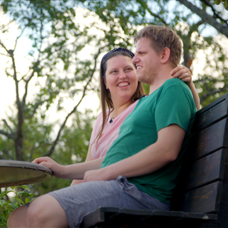 Jan und Diana sitzen Arm in Arm auf Bank