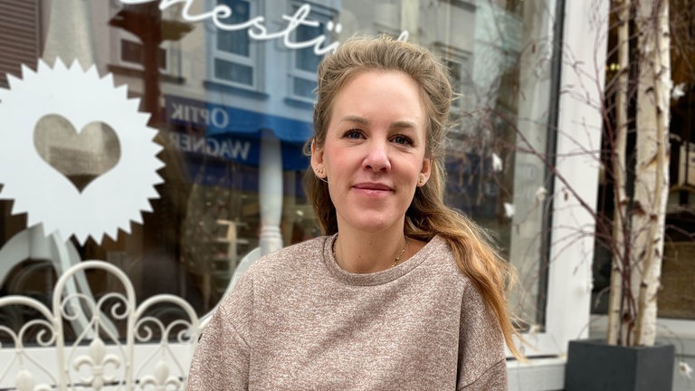 Junge Frau mit blonden Haaren lächelt in Kamera.