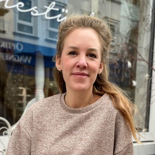 Junge Frau mit blonden Haaren lächelt in Kamera.