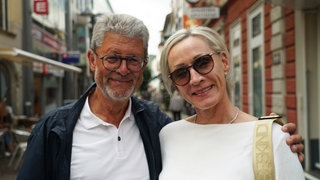 Ein Pärchen mittleren Alters aus Mann und Frau lächeln in die Kamera