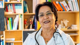 Najiba ist Ärztin und lächelt in die Kamera