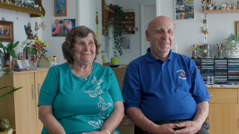 Älteres Ehepaar sitzt nebeneinander und lächelt