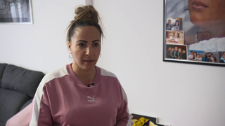 Alleinerziehende Frau sitzt im Zimmer vor weißer Wand