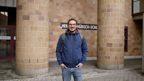 Mann steht vor Klinkersteinmauer einer Berufsschule