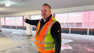 Parkhauswächter Hartmut steht in einer Warnweste in einem Parkhaus in Pforzheim.