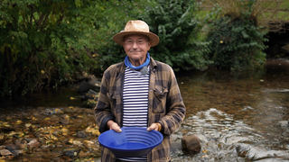 Michael steht in einem Flussbett und lächelt in die Kamera. Er wäscht Gold und erzählt von seiner Leidenschaft.