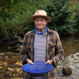 Michael steht in einem Flussbett und lächelt in die Kamera. Er wäscht Gold und erzählt von seiner Leidenschaft.