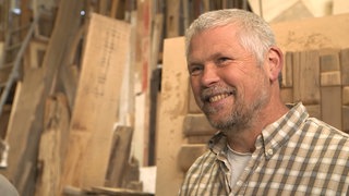 Älterer Herr repariert alte Türen