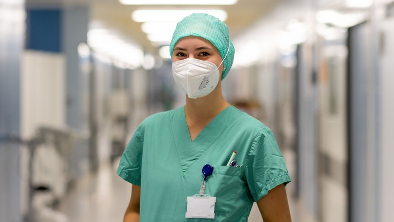 Junge Frau mit OP-Kleidung in grün und Maske. 