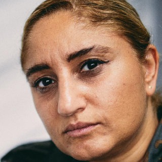 Junge Frau südländischer Herkunft schaut ernst in die Kamera.