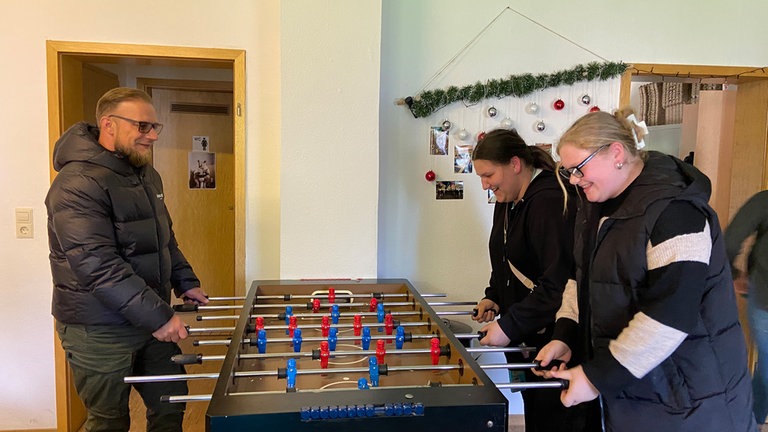 Mann spielt Tischkicker mit Jugendlicher