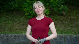 Junge blonde Frau mit rotem T-Shirt, Arbeitshandschuh und Gartenschere.