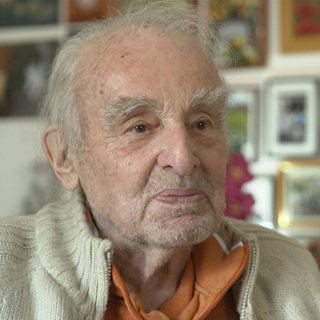 Älterer Mann mit grauen Haaren schaut in die Kamera und lächelt.