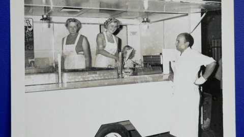 Auf einem alten Schwarz-Weiß-Foto stehen zwei Frauen hinter der Theke eines Imbisswagens. Der Imbiss in St. Goar ist seit fast 60 Jahren Kult.