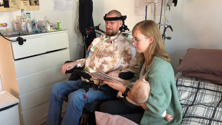 Jan und Anne schauen ein Foto-Buch in der Pflege-WG an.
