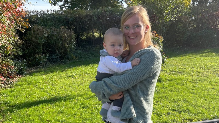 Anne hat ihren Sohn Leo auf dem Arm.