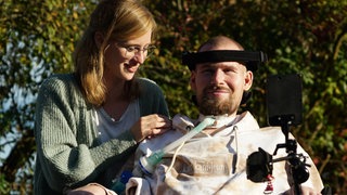 Anne steht neben ihrem Bruder Jan, der im Rollstuhl sitzt.