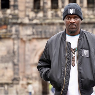 Junger Mann mit dunkler Hautfarbe schaut ernst inKamera.