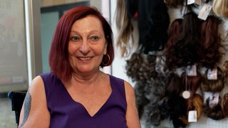 Ältere Dame in ihrem Laden für Perücken