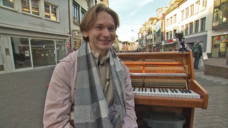 Junger Mann in Fußgängerzone vor seinem Klavier