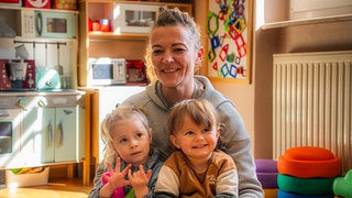 Frau mit zwei Kindern im Spielzimmer