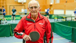 Senior in Sporthalle im Tischtennis-Trainings-Look
