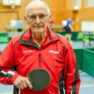 Senior in Sporthalle im Tischtennis-Trainings-Look