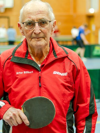 Senior in Sporthalle im Tischtennis-Trainings-Look