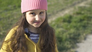 junges Mädchen setzt sich gegen Hundekot im Feld ein