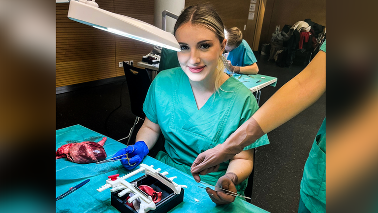 Junge Medizinstudentin mit Herz auf OP-Tisch.