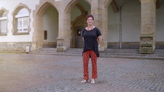 Frau steht vor Schule