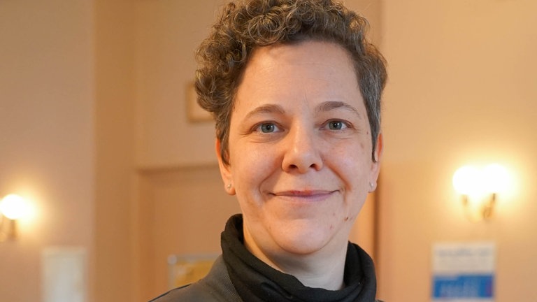 Frau mit grauen Locken lächelt in die Kamera.