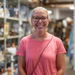 Silke Schulz lacht in die Kamera. Sie bietet Haushaltsauflösungen und Entrümpelungen in Worms an und betreibt dort das „Kaufhaus der Wiederkehr“, wo Secondhandartikel verkauft werden.